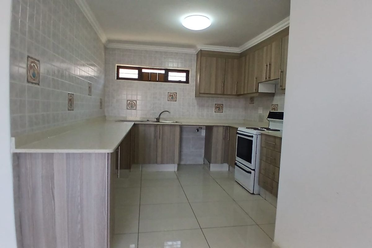 A clean, functional kitchen featuring laminate cabinetry, tiled backsplash, ceramic flooring, and a freestanding stove, offering a neutral space ready for personalization.
