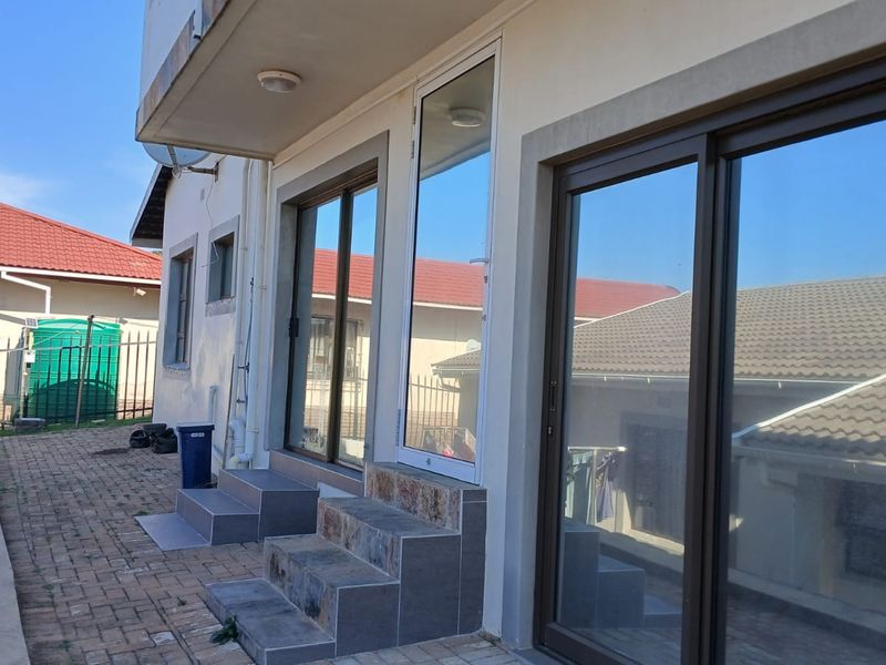 A paved patio area featuring tiled steps and multiple sliding glass doors providing access to the interior of the cottage.