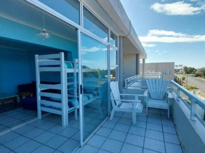 A spacious balcony featuring tiled flooring, a metal balustrade, and large sliding glass doors providing seamless access to the interior living area.