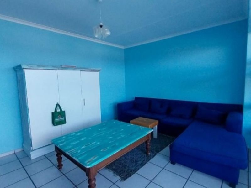 A living area featuring tiled flooring and blue painted walls, providing a functional space with direct access to an adjacent room.