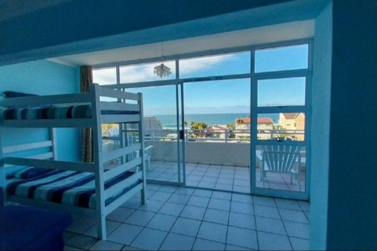 Bedroom featuring tiled flooring and large sliding glass doors that open onto a balcony with ocean views.
