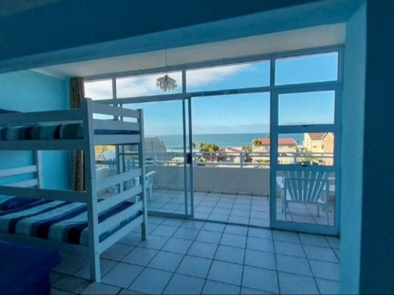 Bedroom featuring tiled flooring and large sliding glass doors that open onto a balcony with ocean views.