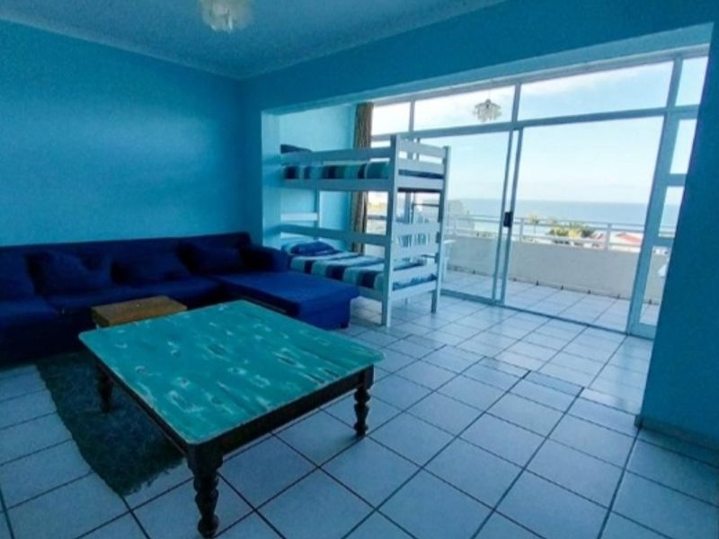 Open plan living area featuring tiled flooring and large sliding glass doors leading to a balcony with ocean views.