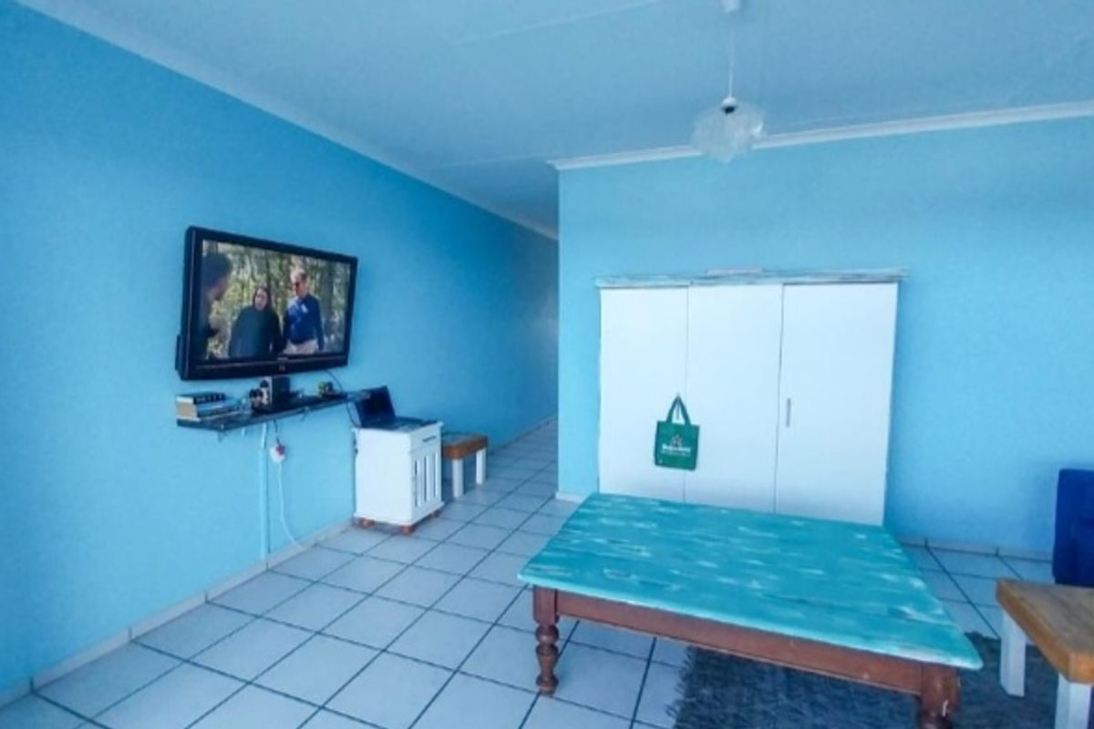 A living area featuring bright blue walls and tiled flooring, providing a blank canvas for potential interior design updates.