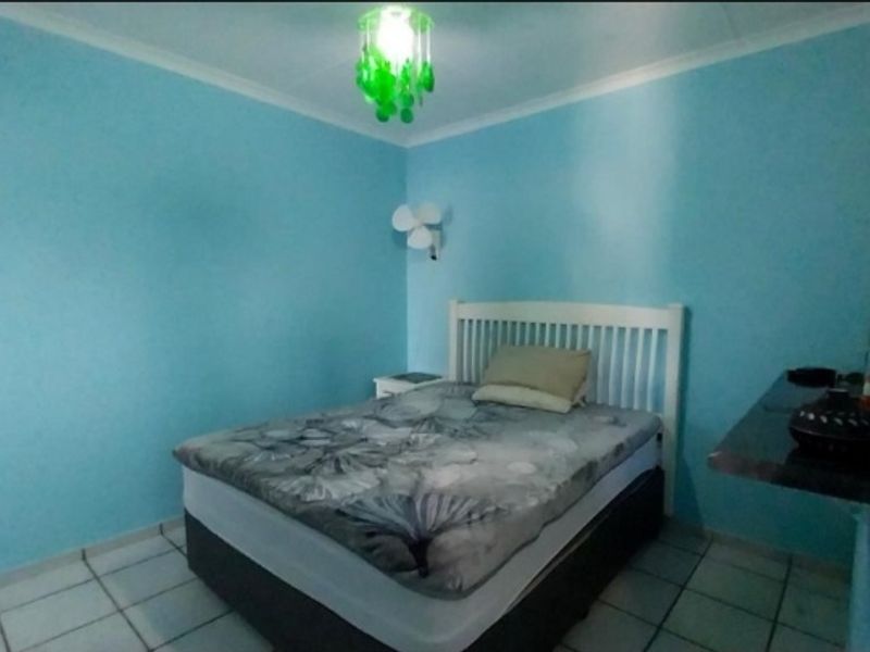 A bedroom featuring light blue walls, tiled flooring, and a wall-mounted fan.