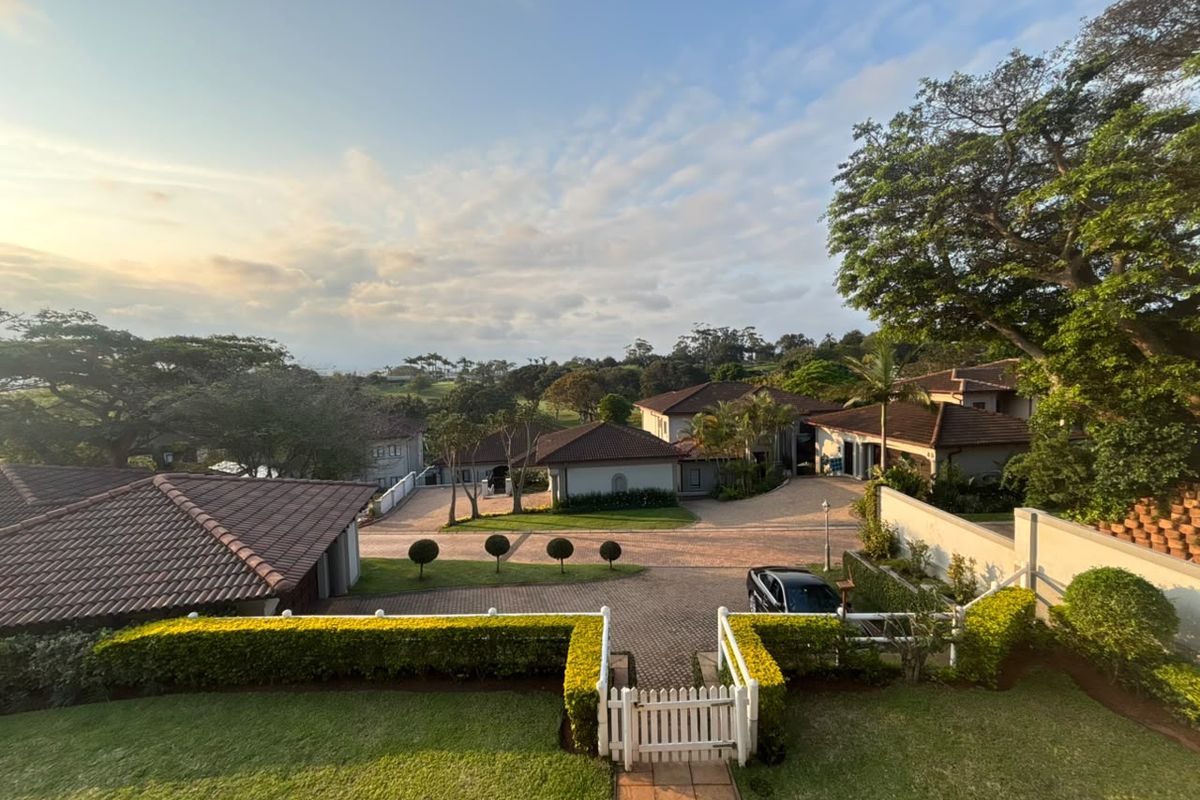 An elevated aerial view of a residential estate featuring paved driveways, tiled roof structures, and well-maintained landscaped gardens.