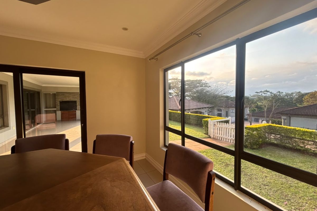 A bright living area featuring large windows with garden views and a sliding door leading to an outdoor patio space.