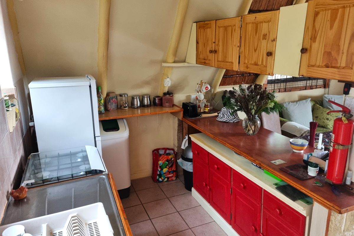 Compact kitchen featuring a gas hob, wooden cabinetry, and a breakfast bar, set within a unique structure with exposed thatch roof elements.
