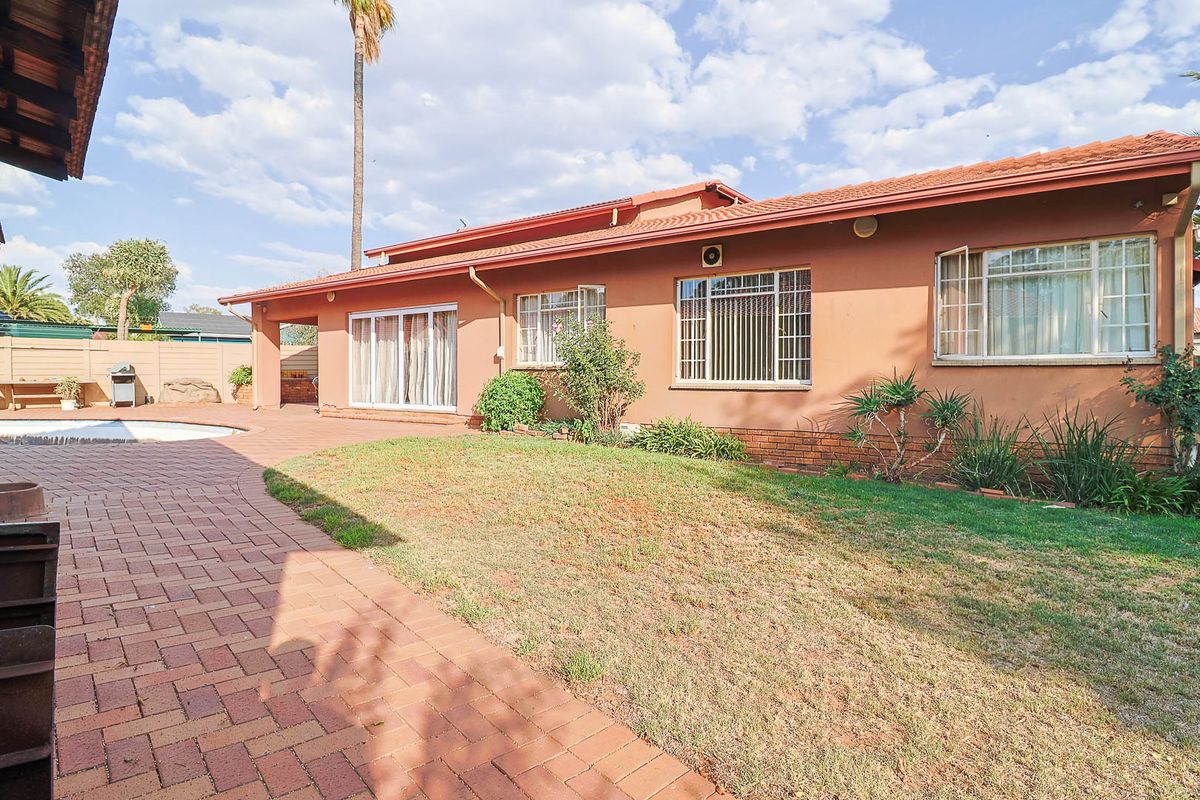 Rear view of the house featuring a paved patio area, swimming pool, and a lawn, with direct access via sliding glass doors.