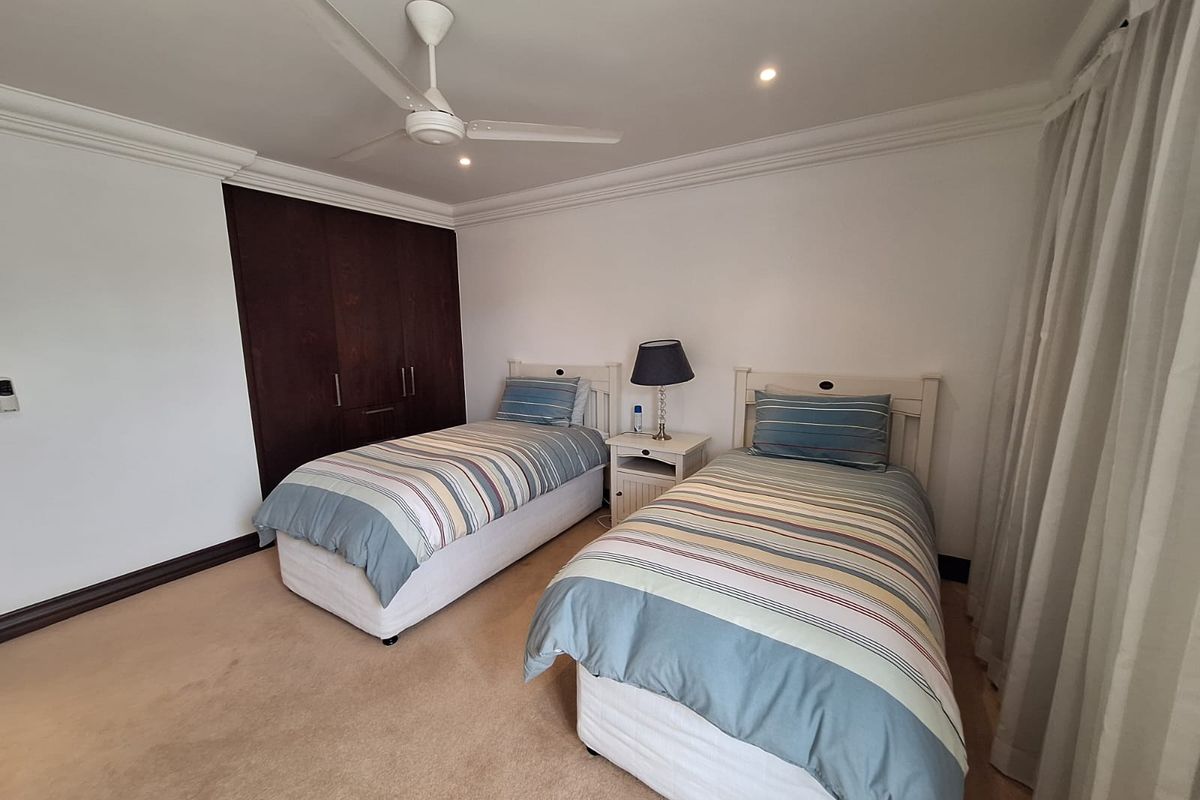 A well-maintained bedroom featuring built-in dark wood cabinetry, recessed ceiling lighting, and a ceiling fan.