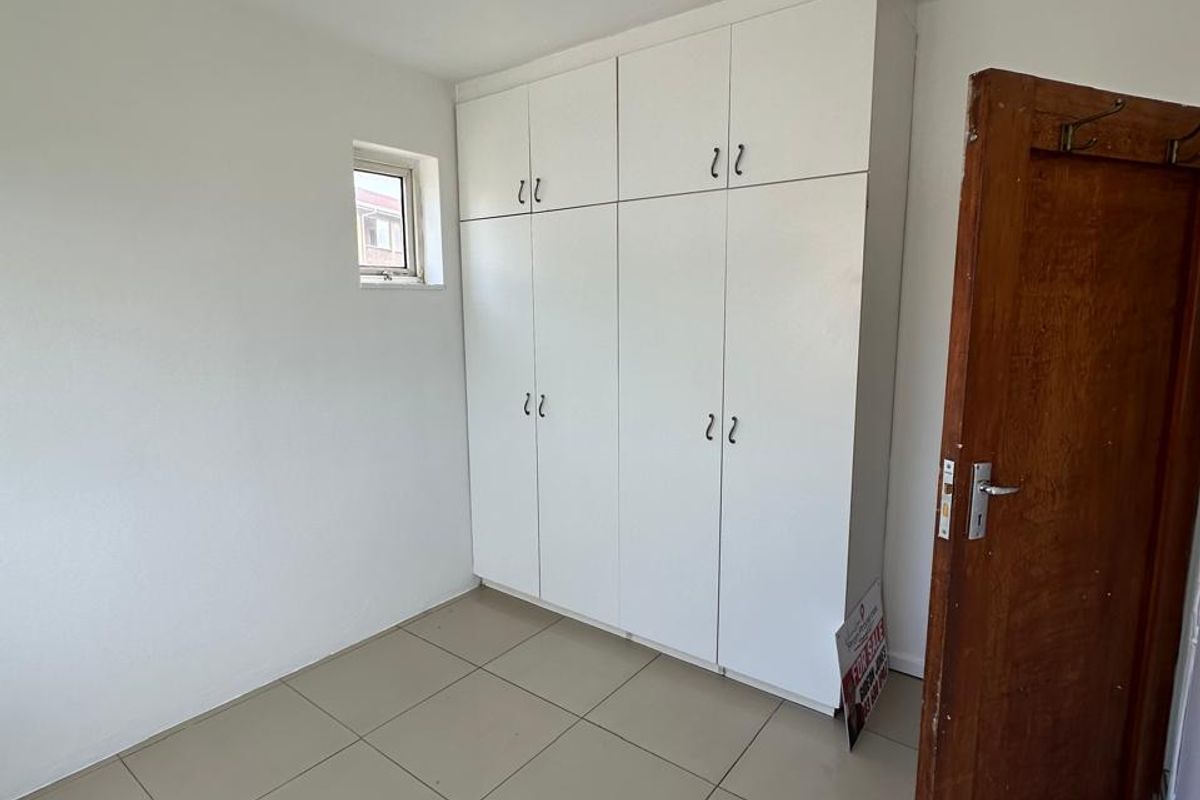 A clean, empty bedroom featuring neutral tiled flooring and white built-in cupboards, offering a blank canvas for personalization.