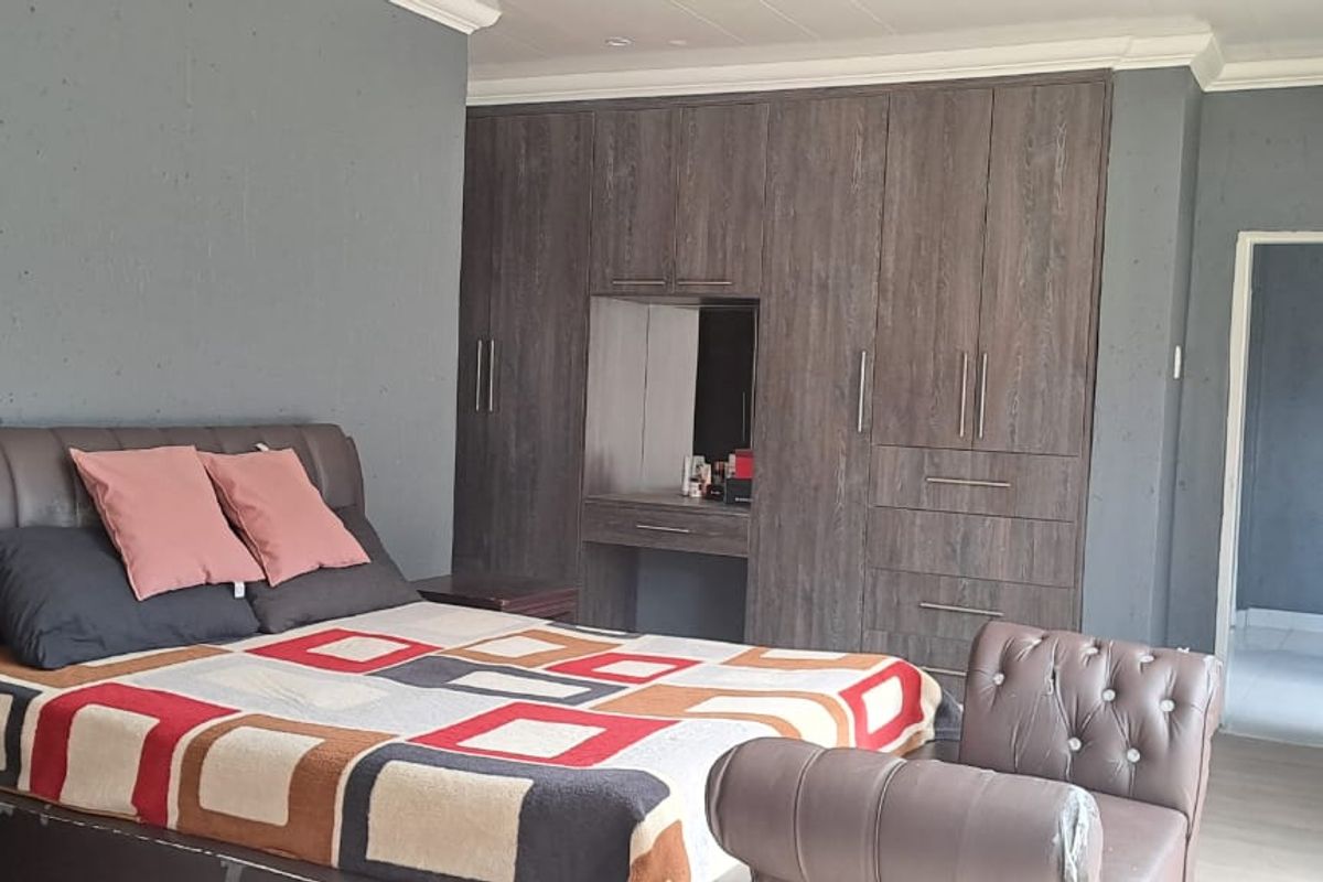 Spacious bedroom featuring extensive built-in wooden cabinetry with integrated vanity and neutral wall finishes.