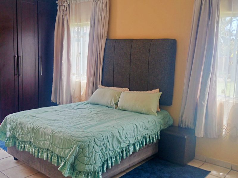 A bedroom featuring tiled flooring and a large built-in wardrobe, offering functional storage space.