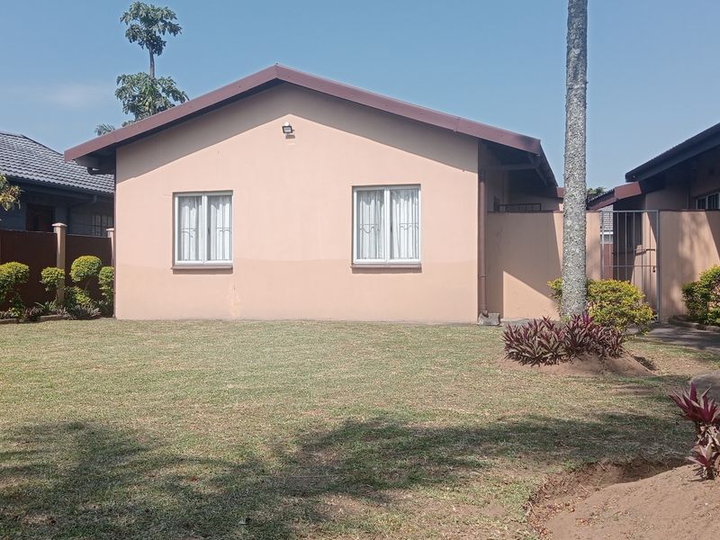 Rear view of the cottage featuring a gabled roof, casement windows, and a private garden area with a perimeter wall.