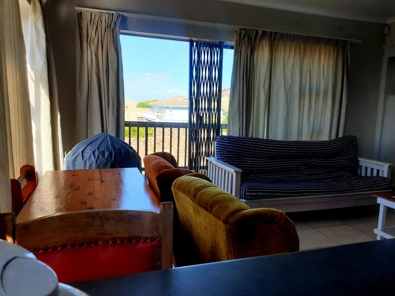 Open plan living area featuring tiled floors and a sliding door leading to a balcony with a security gate.