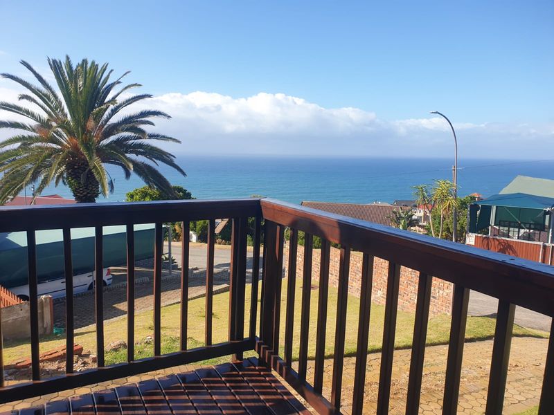 A wooden balcony deck featuring a balustrade with clear views of the surrounding neighborhood and the ocean.
