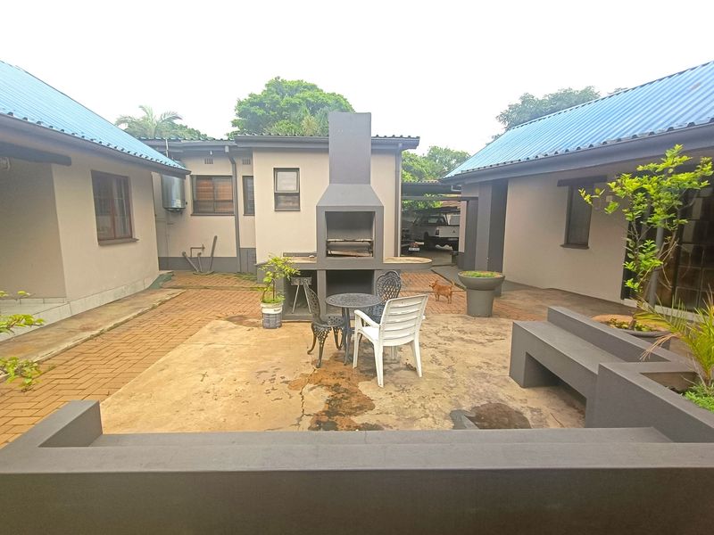 A rear courtyard area featuring a built-in braai, paved patio space, and a fixed concrete bench, providing a functional outdoor entertainment area.