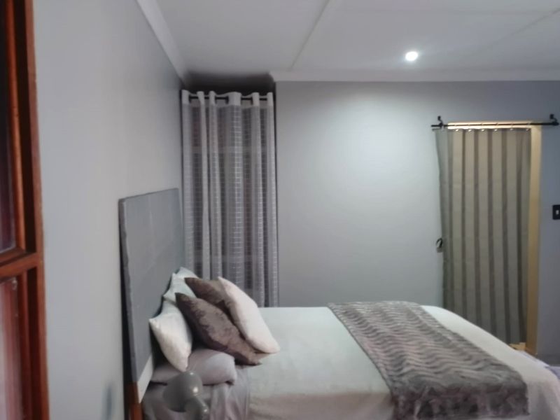 A bedroom featuring neutral grey walls, recessed ceiling lighting, and a sliding door entrance.