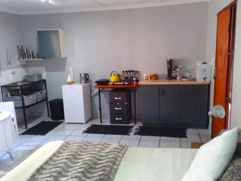 A functional kitchenette area featuring tiled flooring, built-in base cabinetry, and a laminate countertop, providing essential prep space within the apartment.