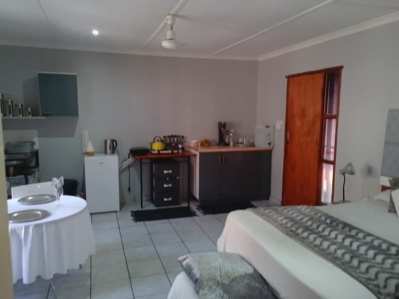 Open-plan studio apartment featuring tiled flooring, built-in cabinetry, and a ceiling fan, offering a functional living and sleeping space.