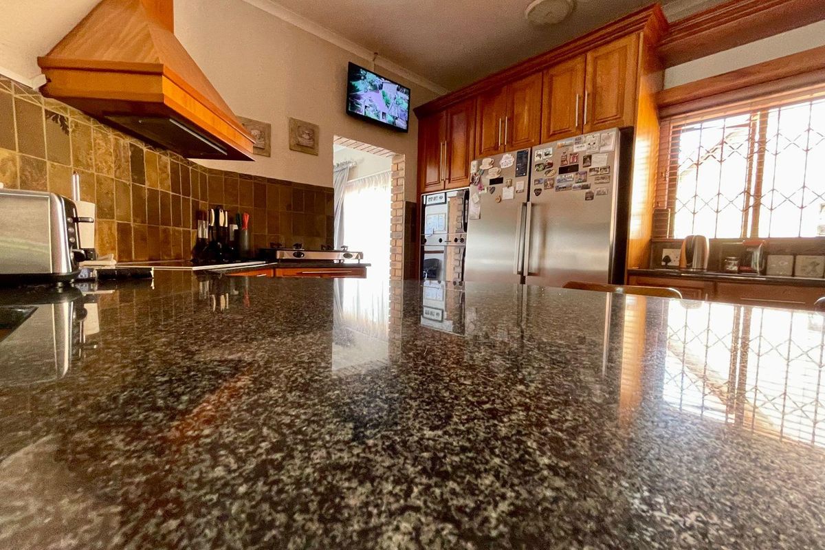 A functional kitchen featuring granite countertops, wooden cabinetry, a built-in oven, and a matching wooden extractor fan canopy.