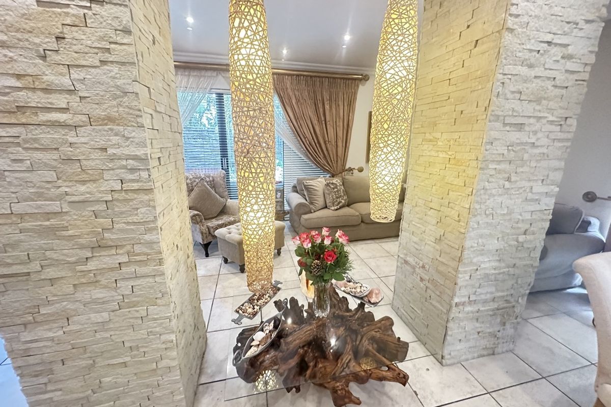 A cozy living area featuring distinctive stacked stone pillars, neutral tiled flooring, and warm recessed lighting, creating an inviting and textured atmosphere.