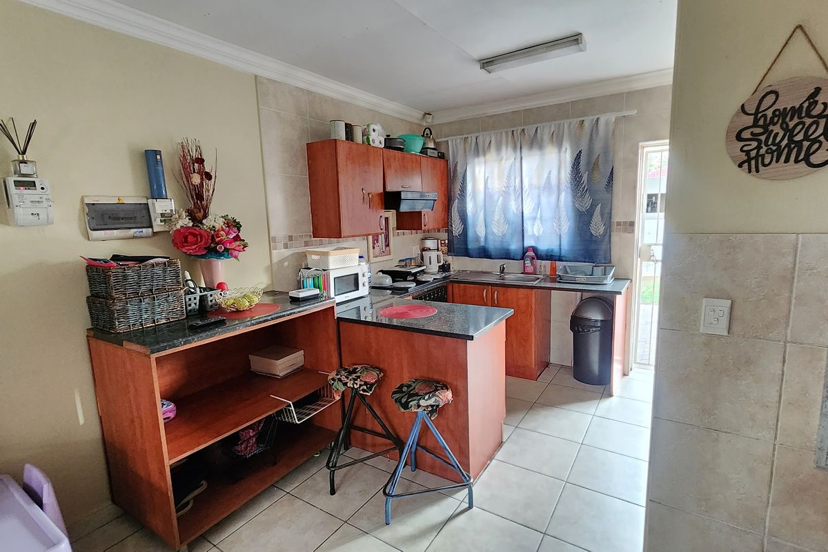 A functional kitchen featuring laminate cabinetry, granite countertops, and ceramic floor tiles, offering a practical layout with direct access to the exterior.