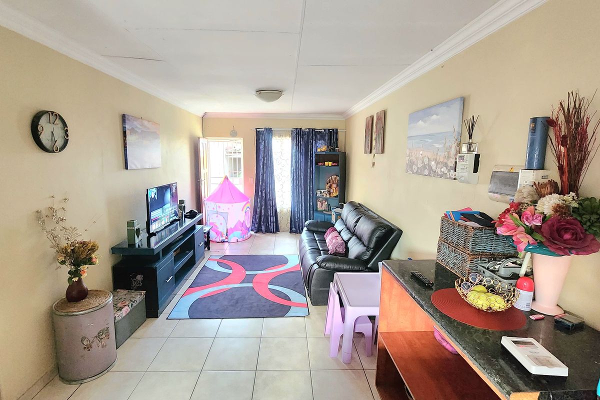 A functional living room featuring tiled flooring and decorative ceiling cornicing, providing a comfortable and practical space for daily living.