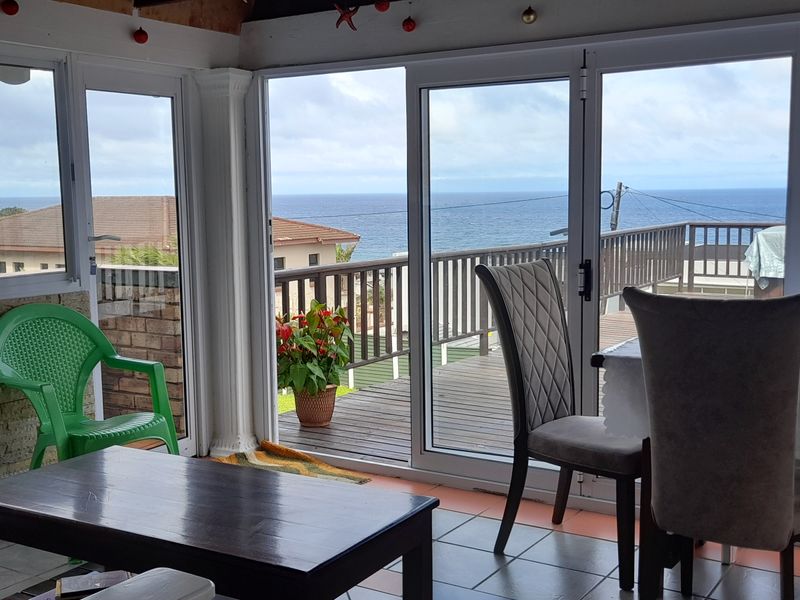 Enclosed patio area featuring large sliding glass doors, tiled flooring, and direct access to an outdoor wooden deck with ocean views.