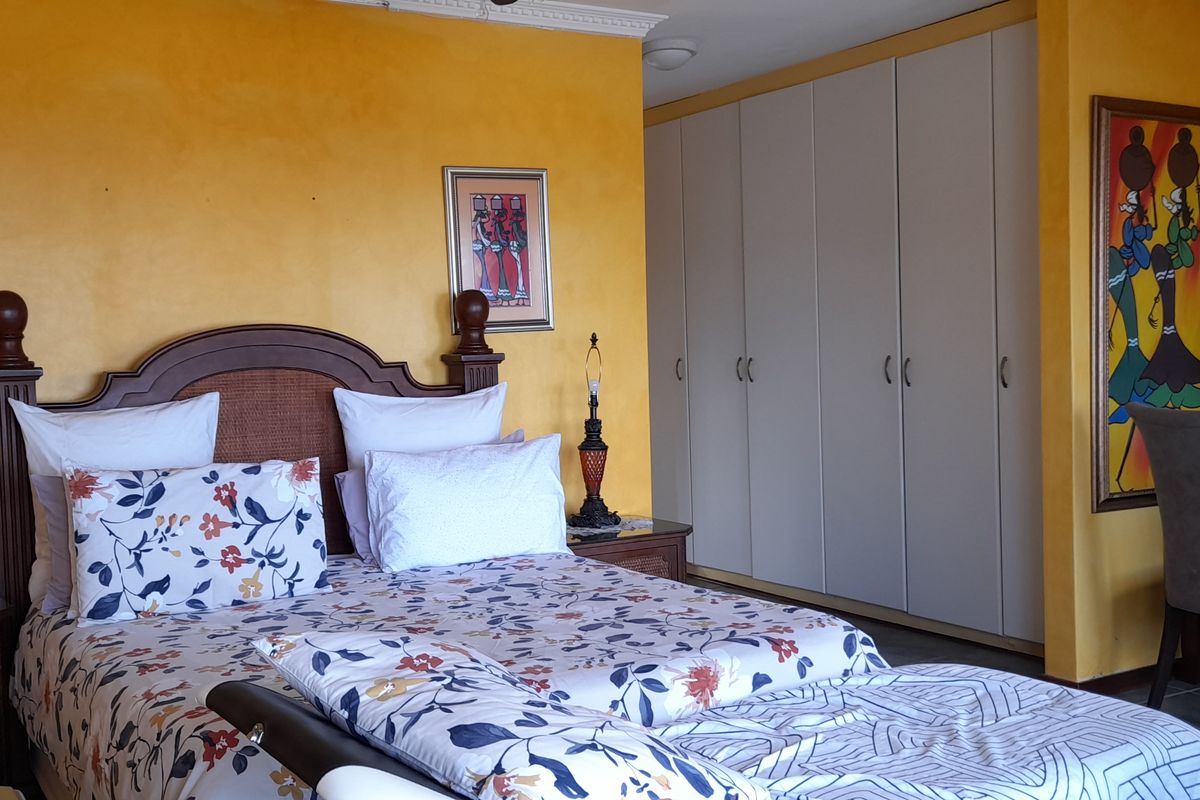 A bedroom featuring built-in cupboards, decorative crown molding, and tiled flooring, finished with warm yellow wall paint.