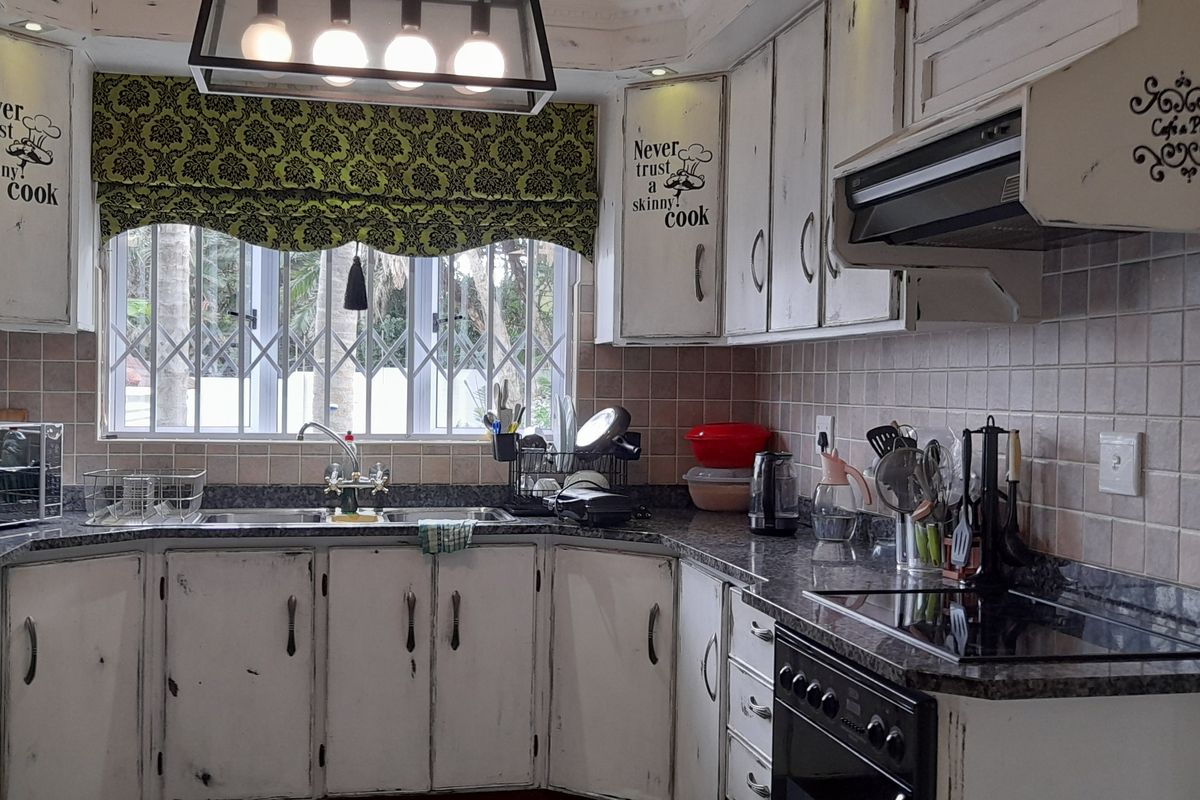 A functional kitchen featuring granite countertops, built-in cabinetry, a double basin sink, and integrated cooking appliances with a tiled backsplash.