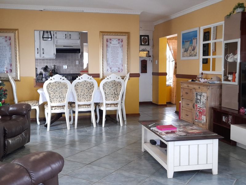 Open-plan living and dining area featuring tiled flooring, coved cornicing, and a convenient pass-through window connecting to the kitchen.