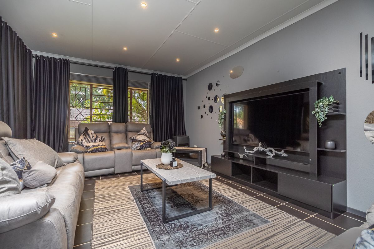 A well-maintained living room featuring tiled flooring, recessed downlighting, and a custom built-in media unit.
