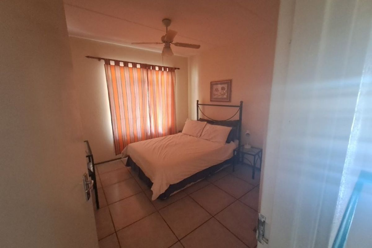 A standard bedroom featuring tiled flooring and a ceiling fan, viewed from the doorway.