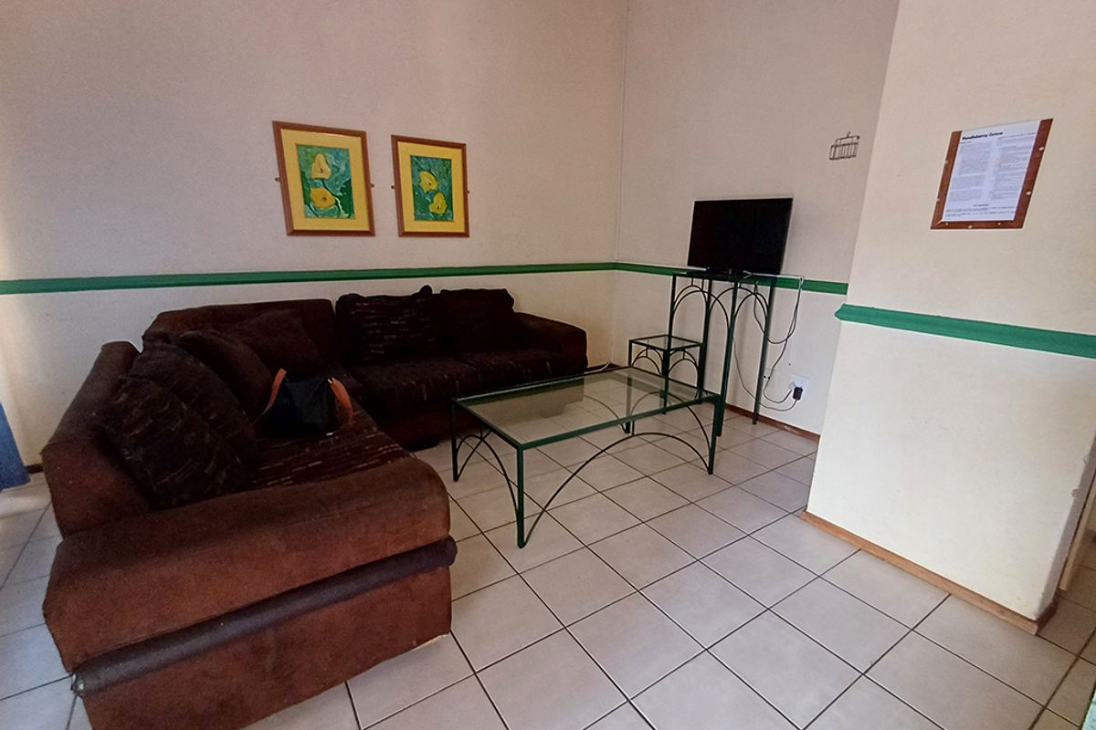 A living area featuring ceramic floor tiles and a painted dado rail, requiring cosmetic updates to improve the overall aesthetic.