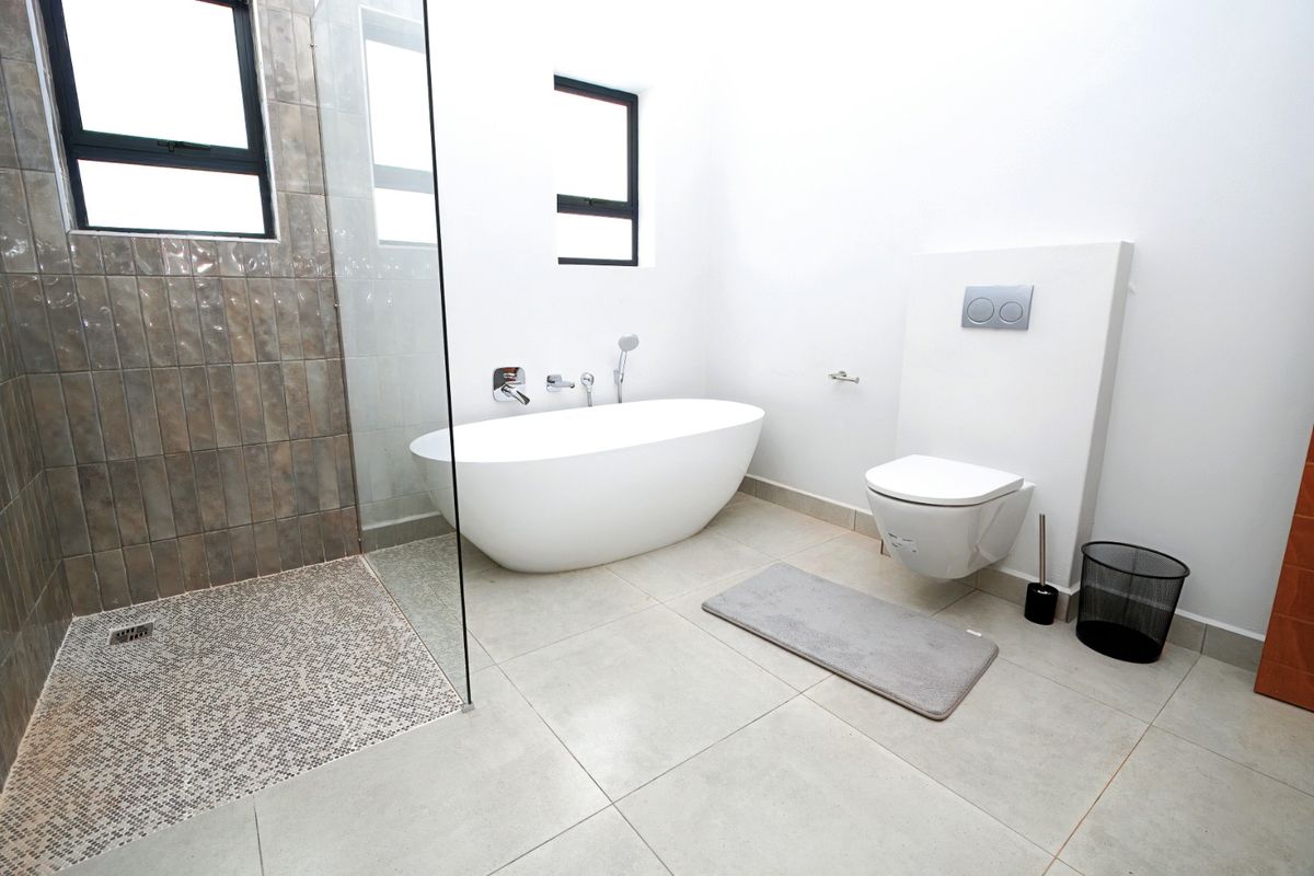Modern bathroom featuring a freestanding bathtub, a glass-enclosed walk-in shower with mosaic floor tiling, and a wall-mounted toilet.
