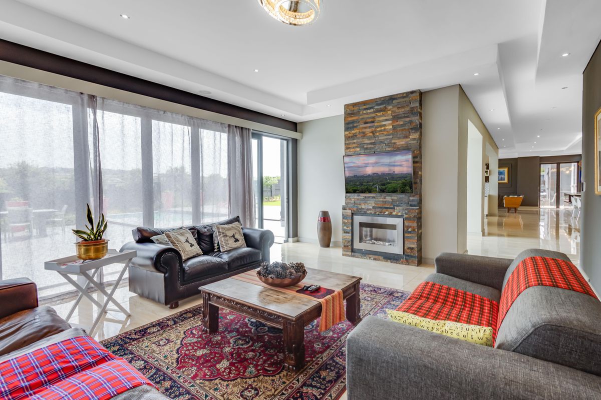 Spacious living room featuring a striking stone-clad fireplace, recessed ceiling lighting, and large sliding glass doors opening to the outdoor area.