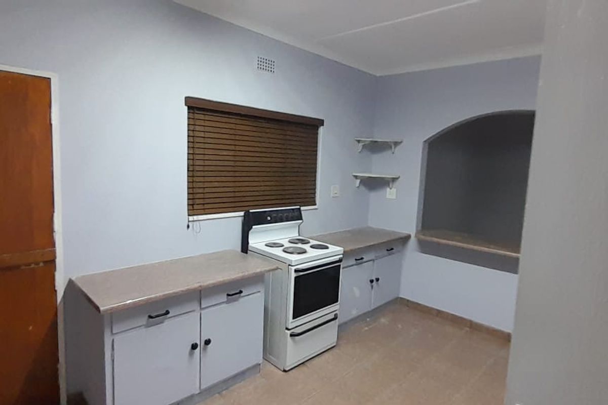 A functional kitchen area featuring built-in cabinetry, a freestanding stove, and a unique arched wall niche, offering a practical space for culinary activities.