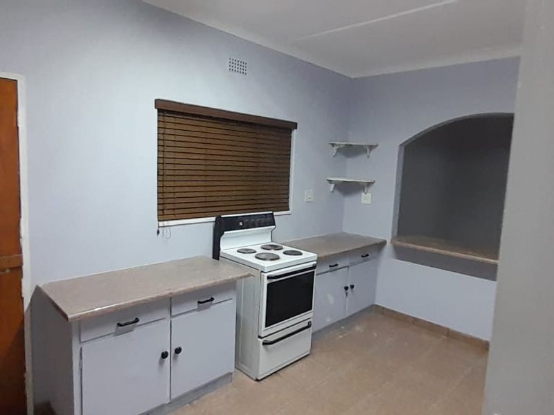 A functional kitchen area featuring built-in cabinetry, a freestanding stove, and a unique arched wall niche, offering a practical space for culinary activities.