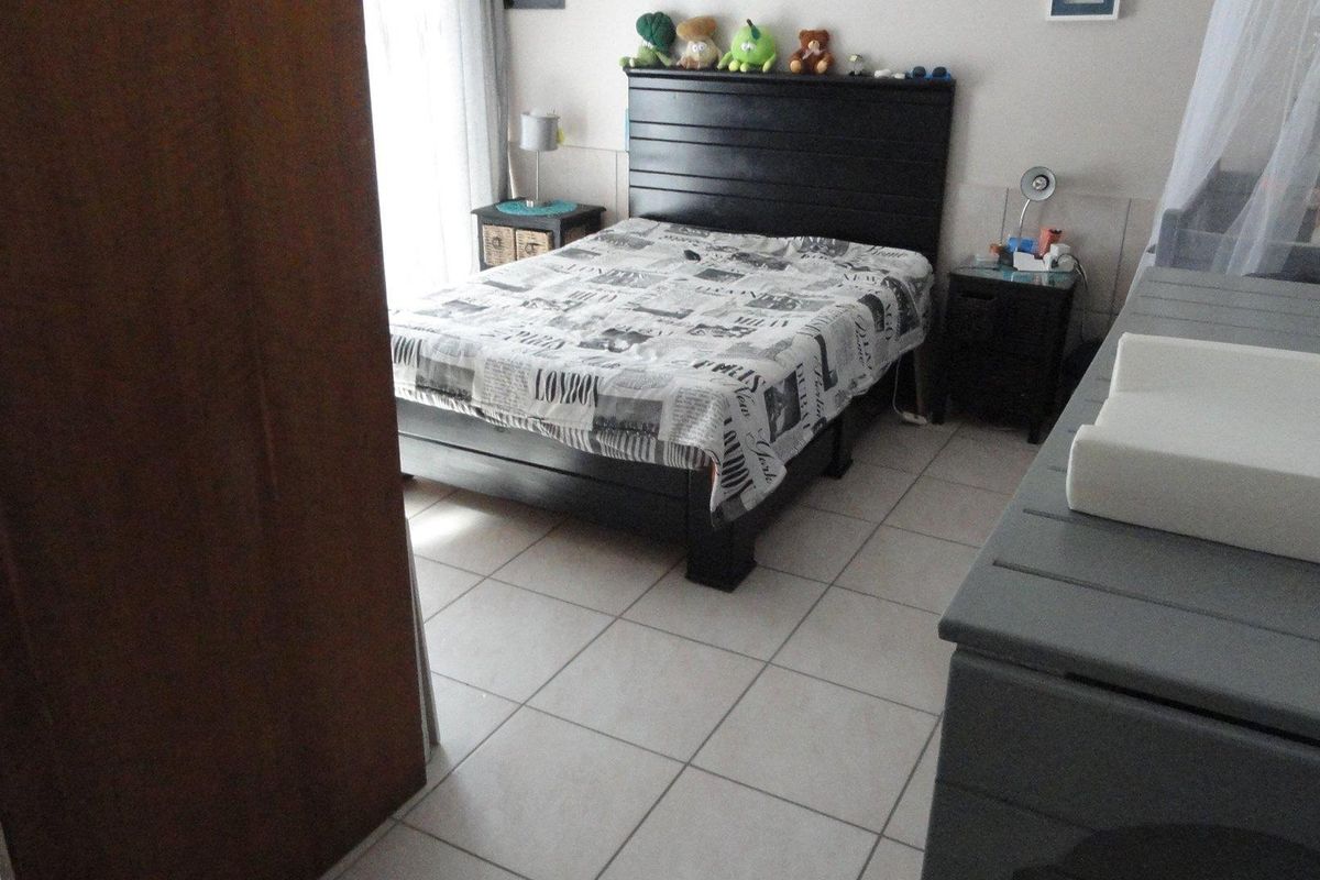 A functional bedroom featuring tiled flooring and a built-in wardrobe, providing a practical space with natural light access.