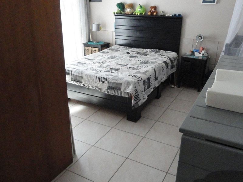 A functional bedroom featuring tiled flooring and a built-in wardrobe, providing a practical space with natural light access.