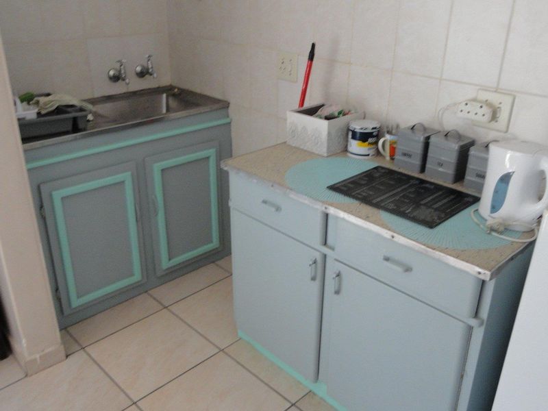 A functional scullery area featuring built-in cabinetry, a stainless steel sink, and tiled splashbacks, offering practical utility space for the home.