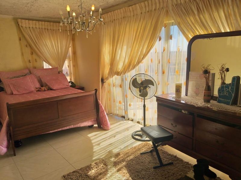 A bedroom featuring tiled flooring, a central chandelier, and a sliding glass door providing natural light.