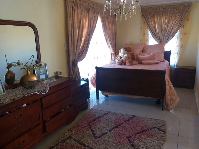 A bedroom featuring tiled flooring and a decorative crystal chandelier, providing a functional space with natural light.
