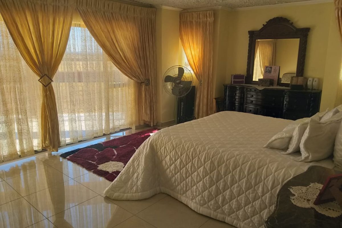 Spacious bedroom featuring polished tile flooring and large sliding glass doors that provide ample natural light.