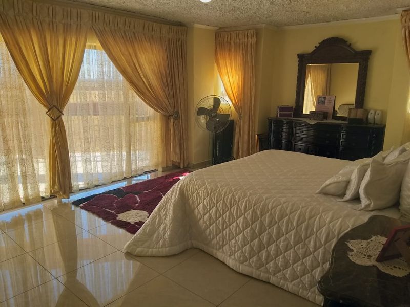 Spacious bedroom featuring polished tile flooring and large sliding glass doors that provide ample natural light.
