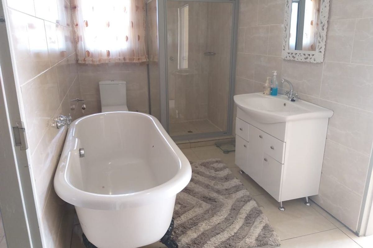 A well-maintained bathroom featuring a freestanding bathtub, a separate shower enclosure, and a modern vanity unit with a basin.
