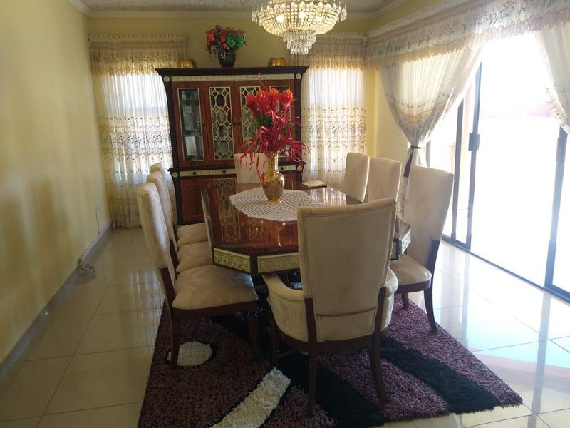 A formal dining room featuring tiled flooring, a crystal chandelier, and large sliding glass doors providing access to the outdoor area.