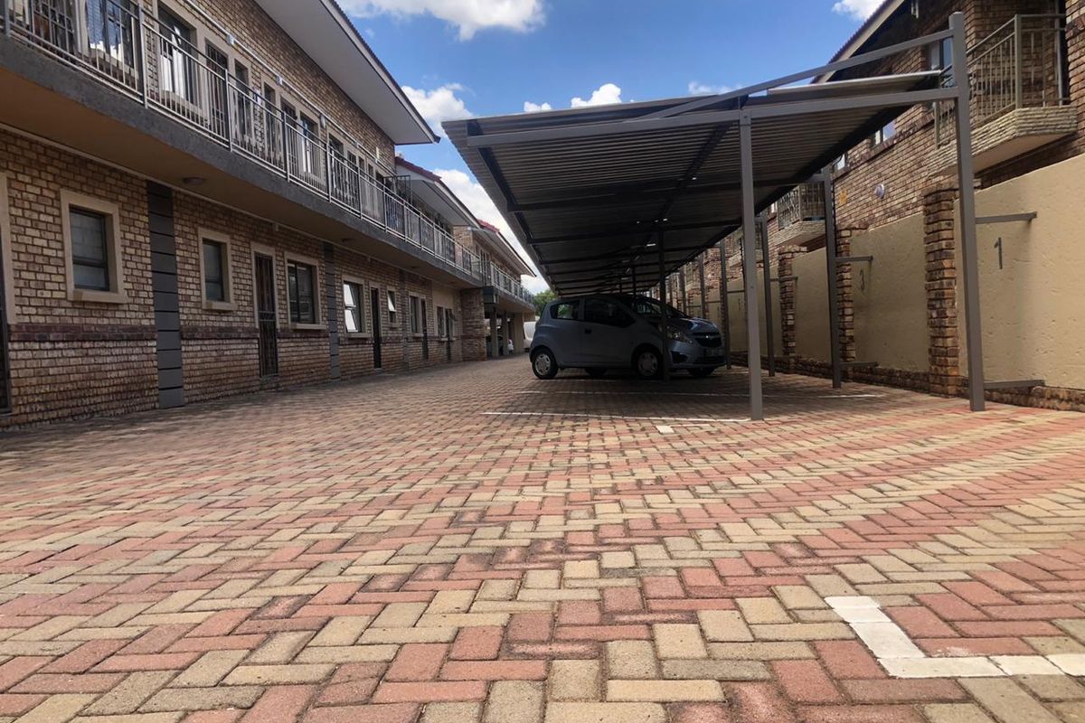 Exterior view of the apartment complex parking area featuring paved driveway and covered parking bays.