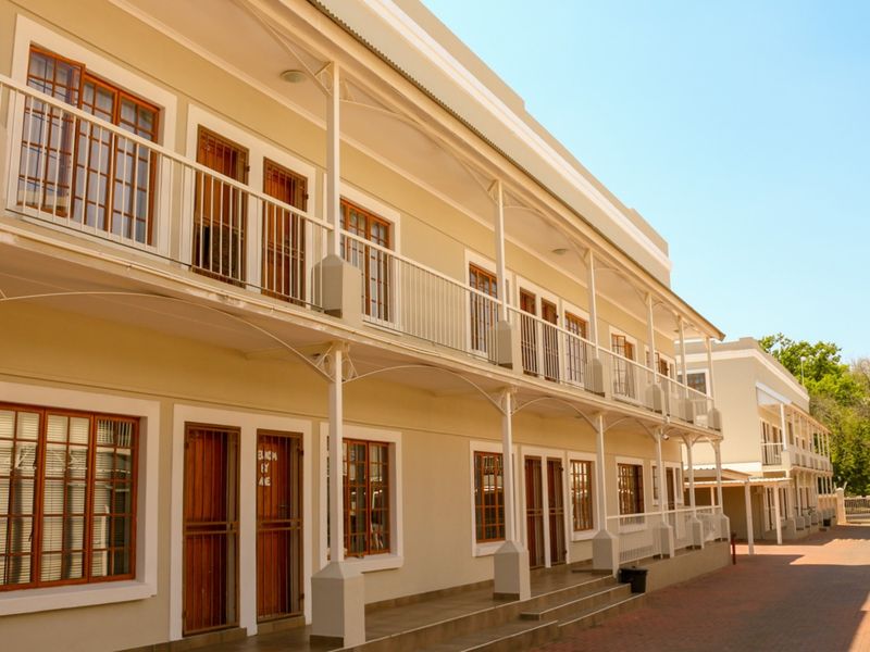 Exterior view of a multi-story apartment building featuring a covered walkway, metal railings, and wooden window frames.